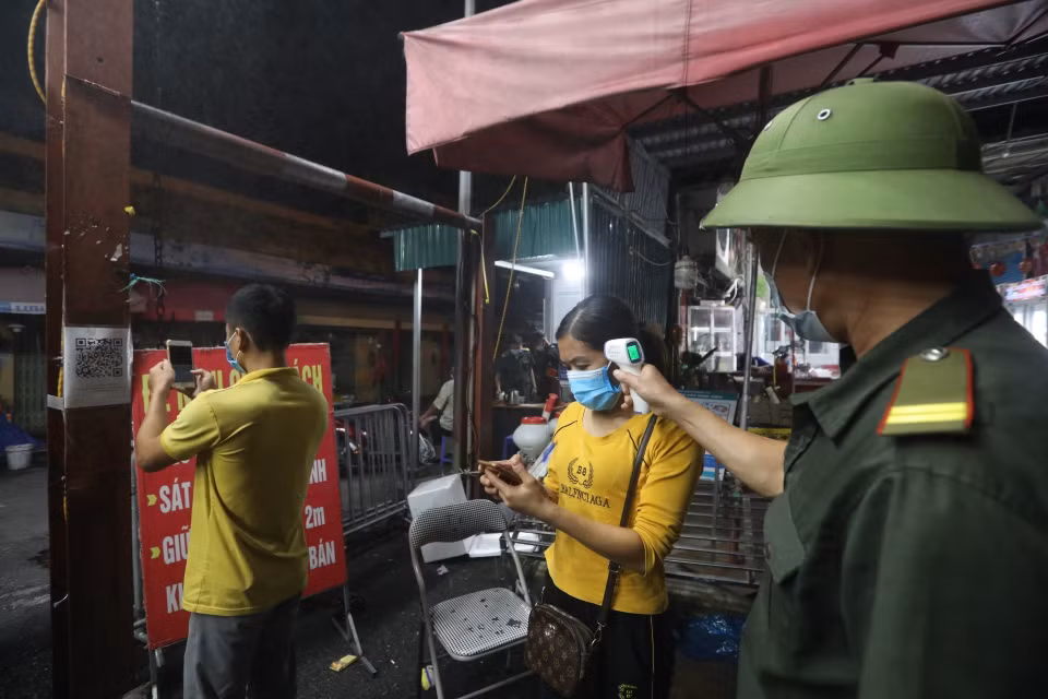 Tiểu thương phải kiểm tra thân nhiệt, khai báo y tế trước khi vào chợ. (Ảnh: Minh Quyết/TTXVN)