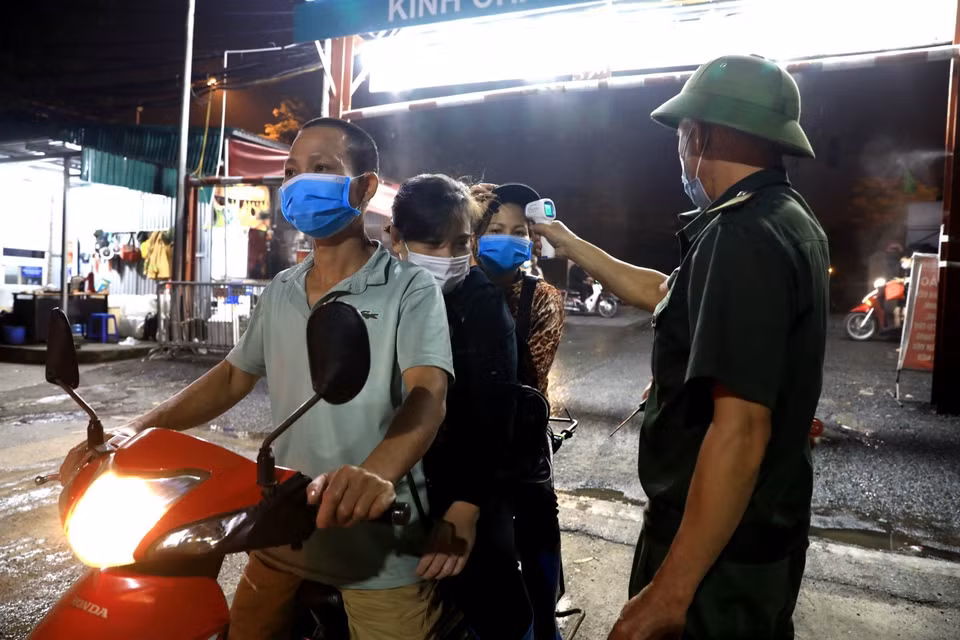 Nhân viên Ban quản lý chợ Long Biên kiểm tra thân nhiệt cho các tiểu thương mỗi khi ra vào. (Ảnh: Thành Đạt/TTXVN)