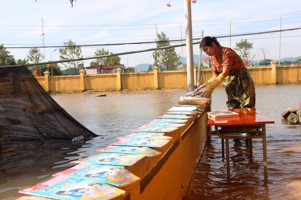 Giáo viên trường Tiểu học Thạch Tân (Xã Tân Lâm Hương, Thạch Hà, Hà Tĩnh) phơi sách cho học trò dù nước lũ chưa rút hết (22/10/2020) (Ảnh: Hoàng Ngà/TTXVN)