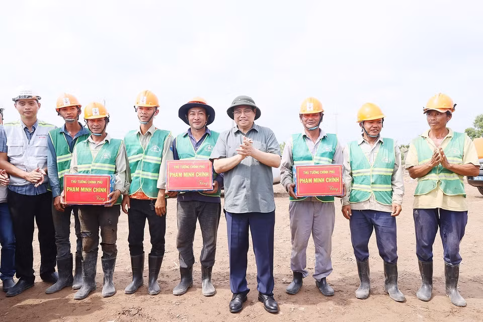 Thủ tướng Phạm Minh Chính tặng quà cho công nhân Dự án Đường bộ Cao tốc Cà Mau-Cần Thơ. (Ảnh: Dương Giang/TTXVN)