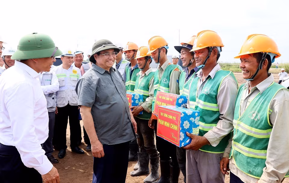 Thủ tướng Phạm Minh Chính tặng quà cho công nhân Dự án Đường bộ Cao tốc Cà Mau-Cần Thơ. (Ảnh: Dương Giang/TTXVN)