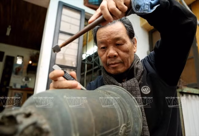 Hơn 60 năm trong nghề, nghệ nhân Nguyễn Văn Hiển đã khắc chữ trên hàng nghìn quả chuông đồng. (Nguồn: Trịnh Bộ/Báo ảnh Việt Nam)