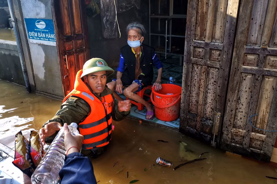 Trung uý Hoàng Trung, Công an huyện Lệ Thuỷ (Quảng Bình) lội nước đưa hàng cứu trợ đến mế già. (Ảnh: TTXVN)