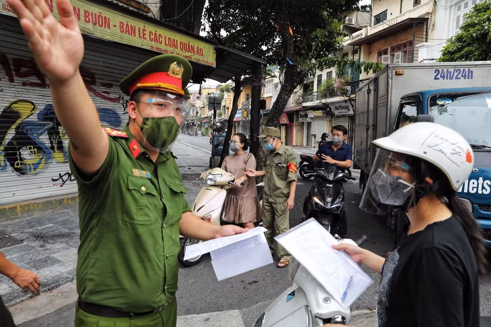 Công an phường Hàng Buồm (Hoàn Kiếm, Hà Nội) kiểm tra chặt chẽ giấy xác nhận đi đường theo quy định mới. (Ảnh: Thành Đạt/TTXVN)