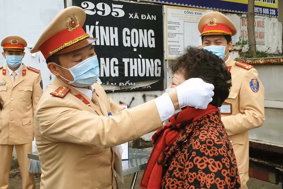 Thực hiện kế hoạch của Công an Thành phố Hà Nội trong đợt cao điểm phòng chống dịch viêm đường hô hấp cấp do chủng mới của virus Corona (nCoV) gây ra, Chi đoàn Thanh niên của Phòng Cảnh sát giao thông, Công an Thành phố Hà Nội phát động phong trào quyên góp tiền mua và phát miễn phí khẩu trang cho người tham gia giao thông, kể cả người đến xử lý vi phạm giao thông tại các đơn vị. Trong ảnh: Cảnh sát giao thông Hà Nội phát khẩu trang miễn phí cho người dân tại phố Xã Đàn. (Ảnh: Doãn Tấn/TTXVN)