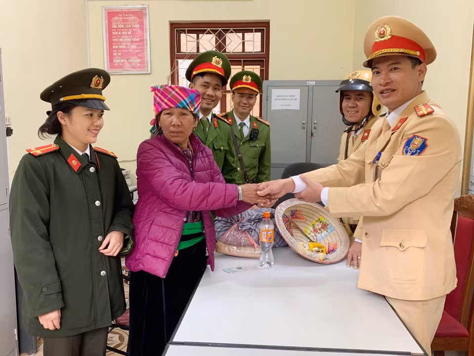 Cán bộ, chiến sỹ Công an huyện Mường La, tỉnh Sơn La hỗ trợ nhu yếu phẩm và kinh phí cho bà Đồng Thị Khân (Yên Bái) trở về nhà do bị lạc đường khi đi thăm con. (Ảnh: TTXVN phát)