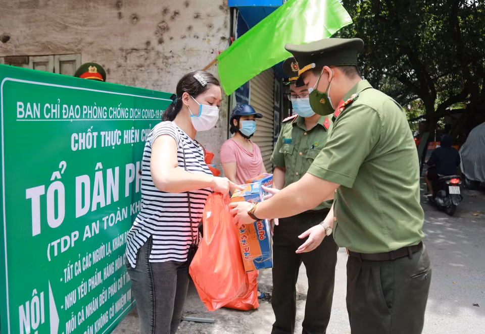 Đại diện Đoàn Thanh niên Công an Hà Nội trao tặng các phần quà cho người dân gặp khó khăn bởi dịch COVID-19. (Ảnh: TTXVN phát)