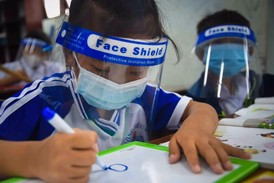 Em Lê Thanh Trúc (lớp 1) nắn nót nét chữ đầu tiên trong năm học đặc biệt. (Ảnh: Huỳnh Anh/TTXVN)