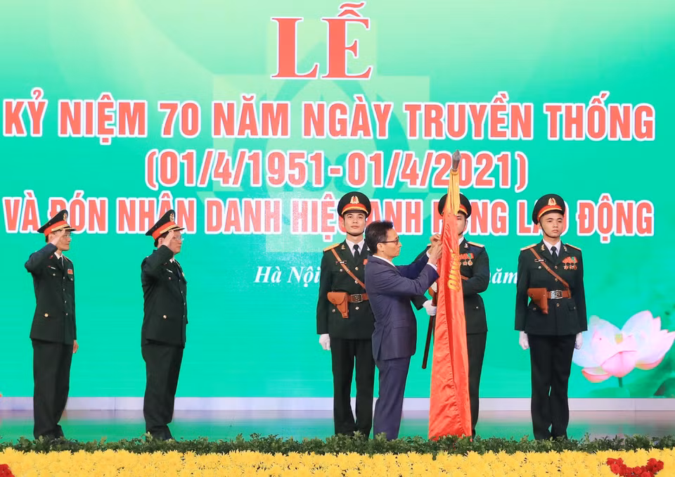Phó Thủ tướng Vũ Đức Đam gắn Danh hiệu Anh hùng Lao động thời kỳ đổi mới lên lá cờ truyền thống của Bệnh viện Trung ương Quân đội 108. (Ảnh: TTXVN)