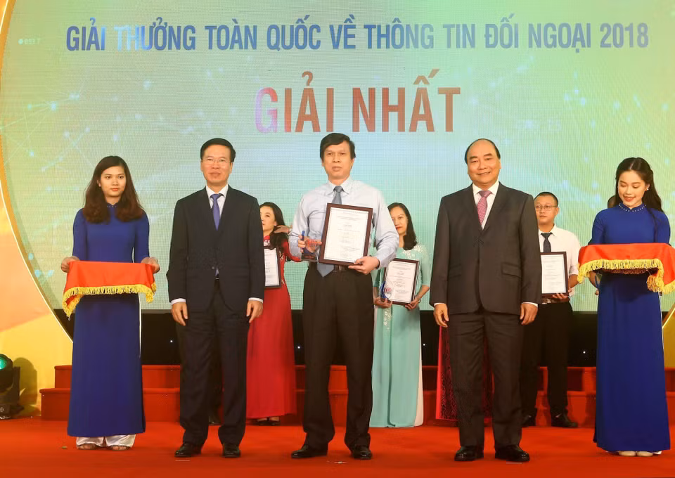 Thủ tướng Nguyễn Xuân Phúc và Trưởng ban Tuyên giáo Trung ương, Trưởng ban Chỉ đạo Công tác thông tin đối ngoại Trung ương Võ Văn Thưởng trao giải nhất Giải thưởng toàn quốc thông tin đối ngoại năm 2018 cho tác giả Lê Trí Dũng (TTXVN), ngày 7/6/2019, tại Hà Nội. (Ảnh: Doãn Tấn/TTXVN)