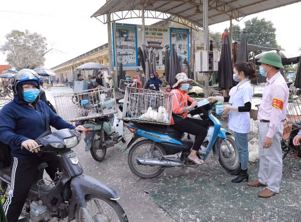 Kiểm tra thân nhiệt tất cả khách vào chợ gia cầm Hà Vĩ (Thường Tín, Hà Nội). (Ảnh: Vũ Sinh/TTXVN)