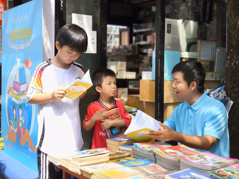 Anh Nguyễn Văn Tâm thường xuyên đưa hai con đến đường sách để các bé làm quen với việc đọc sách. (Ảnh: Huỳnh Phúc Hậu/TTXVN)