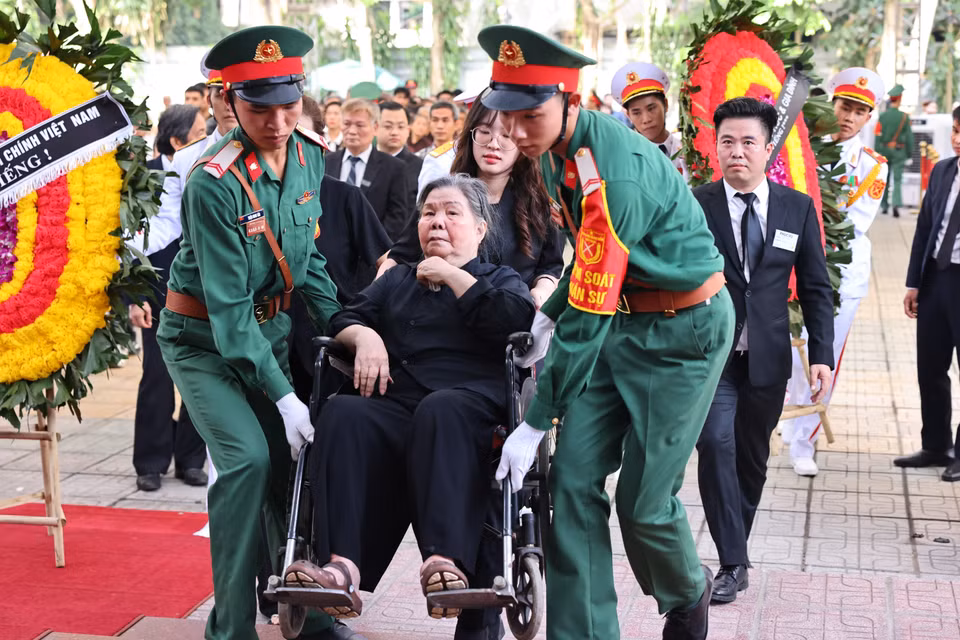 Lực lượng kiểm soát quân sự hỗ trợ, giúp bà Đặng Thị Phúc, giáo viên tiểu học của Tổng Bí thư Nguyễn Phú Trọng, năm nay đã 92 tuổi, sức khỏe đã giảm nhiều, đến Nhà tang lễ Quốc gia số 5 Trần Thánh Tông để được tiễn biệt học trò lần cuối. (Ảnh: TTXVN)