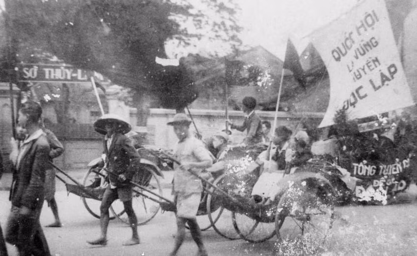 Thông qua các đoàn thể cứu quốc, Mặt trận Việt Minh đã tuyên truyền, vận động quần chúng tự nguyện và hăng hái tham gia các phong trào sản xuất, cứu đói, hũ gạo tiết kiệm, tuần lễ vàng, bình dân học vụ... nhằm phát huy tinh thần yêu nước của Nhân dân để vượt qua những khó khăn về kinh tế, tài chính. Trong ảnh: Nhân dân lao động Thủ đô cổ động cho ngày Tổng tuyển cử đầu tiên. (Nguồn: TTXVN 