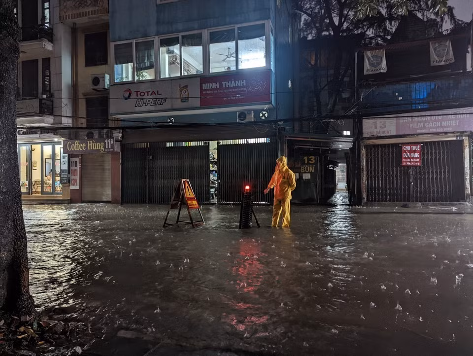 Công nhân Công ty Thoát nước Hà Nội ứng trực, cảnh báo khu vực ngập. (Ảnh: Mạnh Khánh/TTXVN)