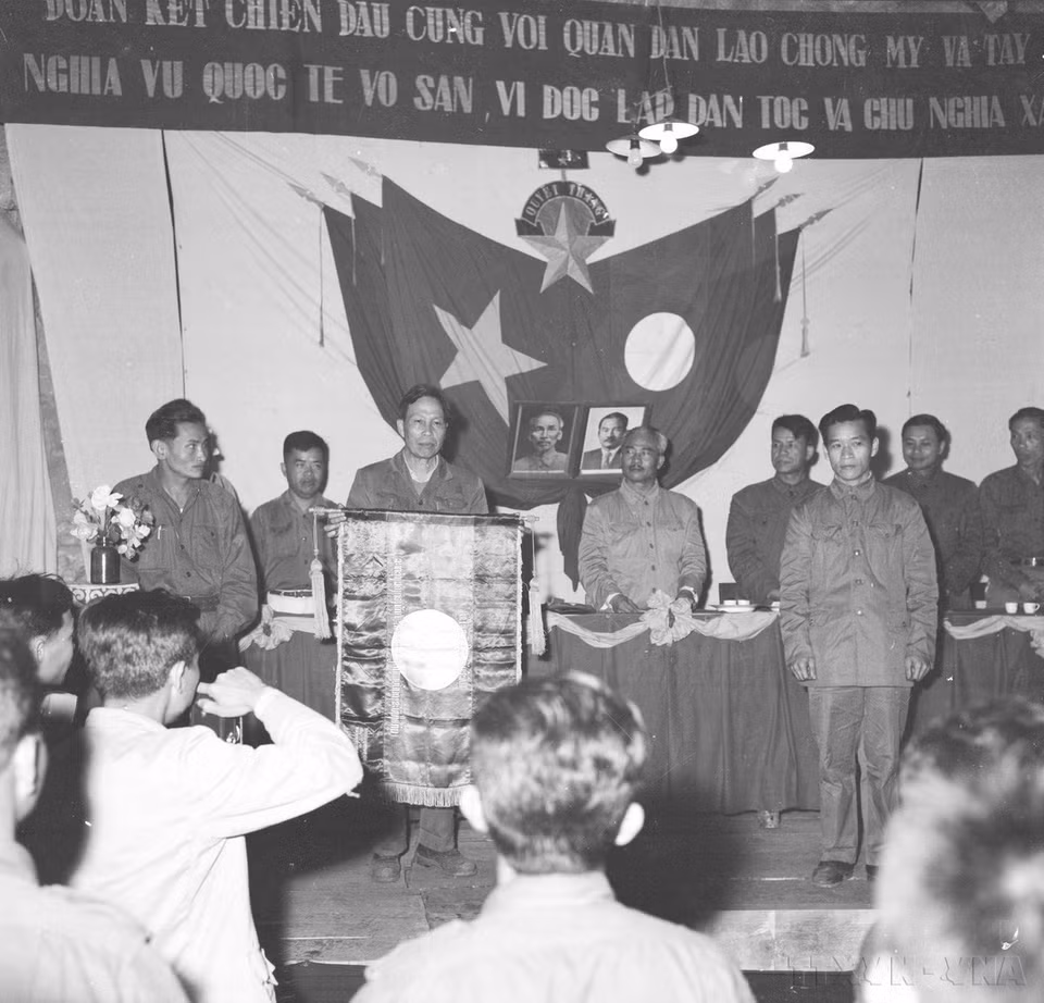Ông Thao Khừn, Chủ nhiệm Tổng cục Hậu cần QĐND Lào trao tặng đơn vị quân tình nguyện Việt Nam mặt trận miền Tây lá cờ "Bách chiến - Bách thắng". (Ảnh: TTXVN)