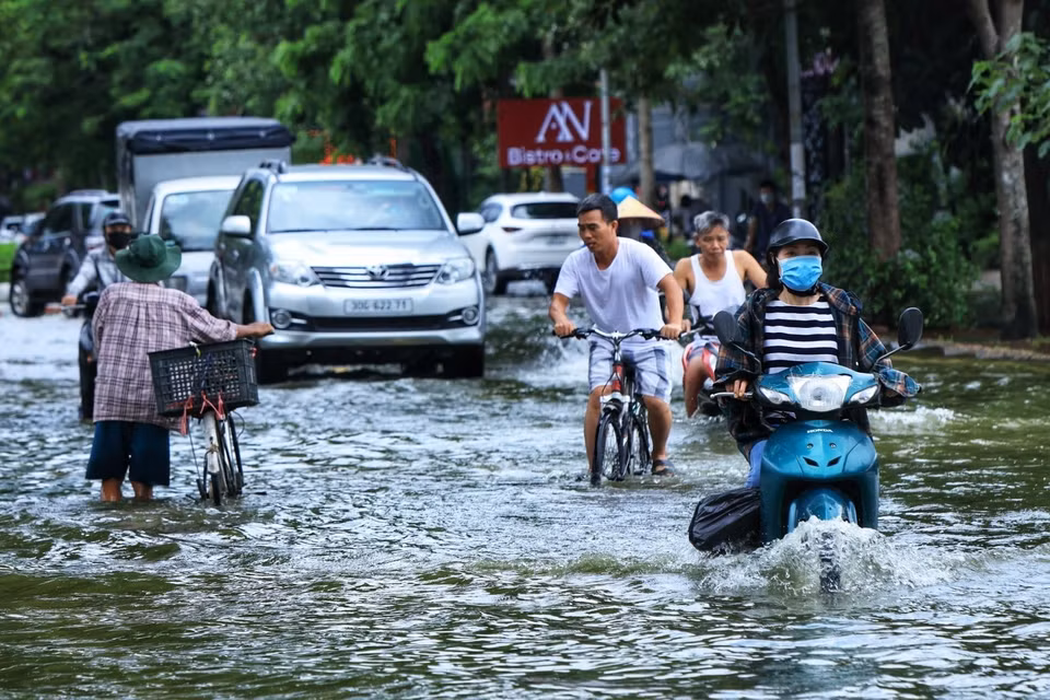 Nước ngập sâu khiến người dân đi lại khó khăn. (Ảnh: Tuấn Anh/TTXVN)
