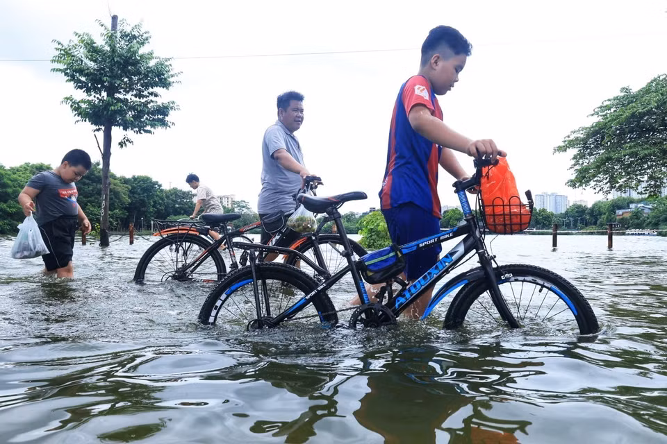 Người dân không thể đạp xe đi qua đoạn đường do nước ngập sâu. (Ảnh: Tuấn Anh/TTXVN)