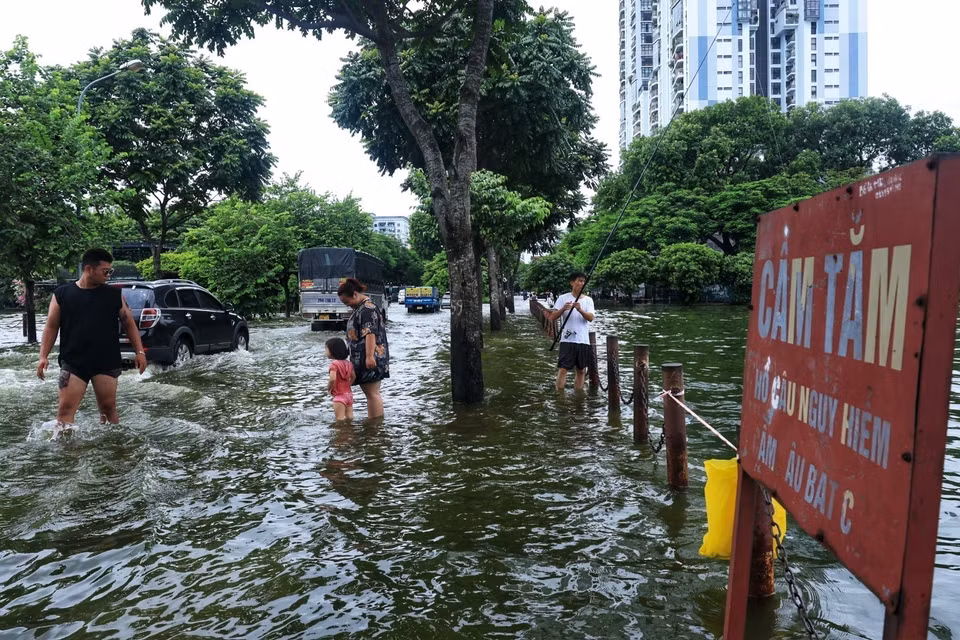 Người dân đứng hướng dẫn các phương tiện khi đi qua chỗ ngập. (Ảnh: Tuấn Anh/TTXVN)