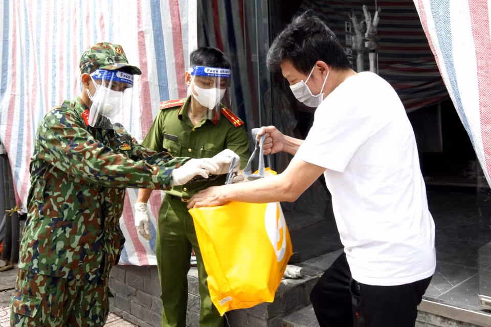 Cán bộ chiến sỹ Trung đoàn 1, Sư đoàn 9, Quân đoàn 4 cùng cảnh sát khu vực phường Võ Thị Sáu, Quận 3 trao túi hỗ trợ cho những người ở trọ có hoàn cảnh khó trong những ngày thành phố giãn cách xã hội. (Ảnh: Thanh Vũ/TTXVN)