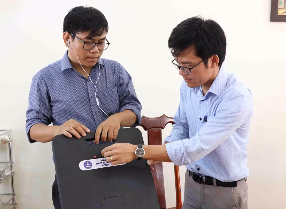 Thầy Tôn Thất Trường Nam (bên trái) và thầy Trần Quốc Lâm giới thiệu về máy phát hiện gian lận thi cử. (Ảnh: Phạm Cường/TTXVN)