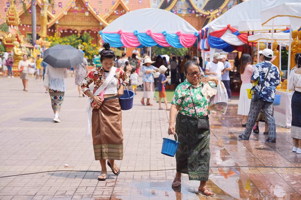 Người dân Lào tới chùa để thực hiện nghi lễ tắm Phật vào dịp Năm mới.(Ảnh: Đỗ Bá Thành/TTXVN)