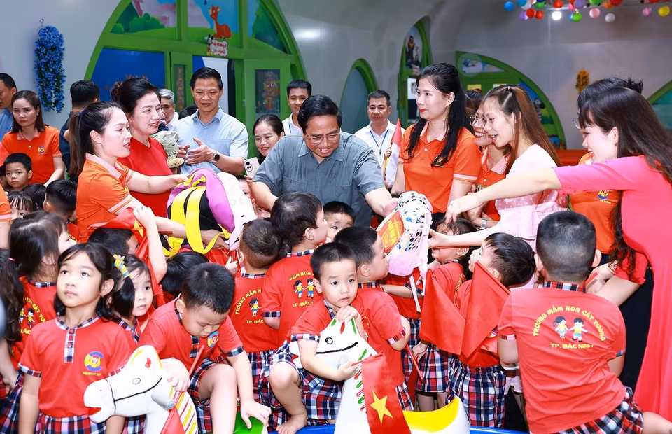 Thủ tướng Phạm Minh Chính tặng quà học sinh trường mầm non Cát Tường trong khu nhà ở xã hội tại thành phố Bắc Ninh. (Ảnh: Dương Giang/TTXVN)