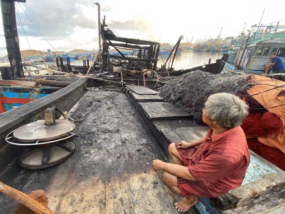 Ngư dân Lê Văn Tá (thị xã Hoài Nhơn) tần ngần bên chiếc tàu cháy rụi. (Ảnh: Tường Quân/TTXVN)