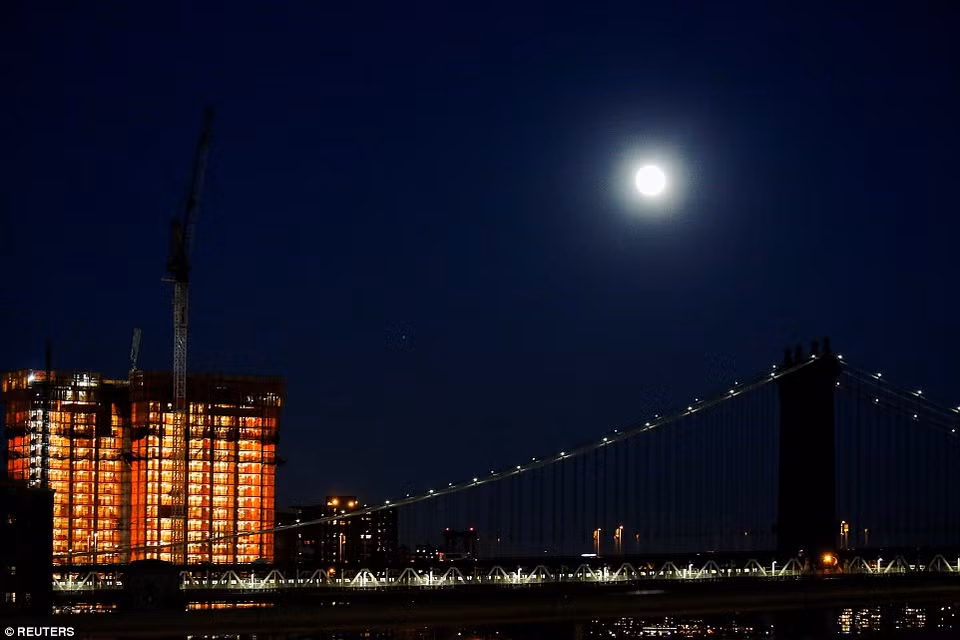 Người dân ở gần cầu Manhattan, New York, Mỹ ngắm nhìn Siêu Trăng. (Nguồn: Reuters)