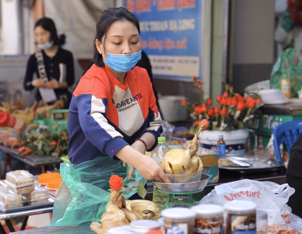 Gà luộc sẵn, buộc cánh tiên, ngậm hoa để cúng là một trong những mặt hàng bán chạy nhất sáng 30 Tết tại chợ Hàng Bè. (Ảnh: Hoàng Hiếu/TTXVN)