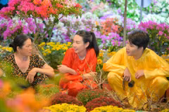 Hoa hậu Thùy Tiên và "anh trai" Quang Trung trải nghiệm bán hoa Tết bên bến sông Sài Gòn. (Ảnh: CTV/Vietnam+)