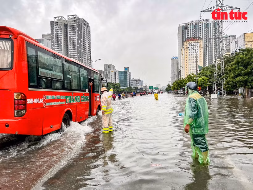 Đội CSGT số 6 tập trung phân luồng, điều tiết phương tiện tại nút giao thông trọng điểm Mai Dịch - Vành đai 3 đang ngập trong nước. (Ảnh: Báo Tin tức/TTXVN)