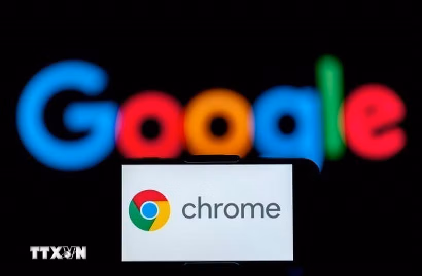 Biểu tượng Chrome trên màn hình điện thoại và biểu tượng Google (phía sau). (Ảnh: Getty Images/TTXVN)