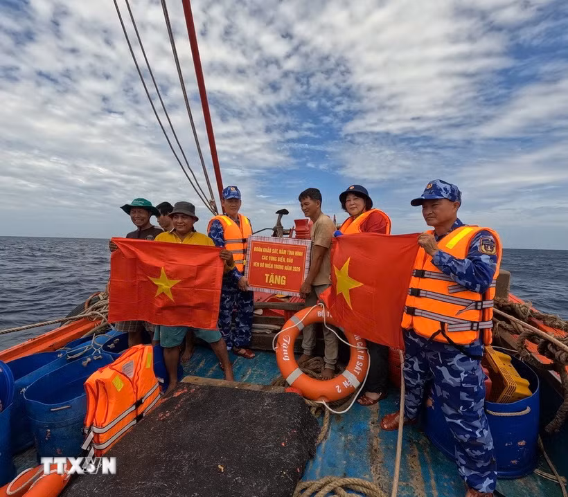 Đoàn công tác của Bộ Tư lệnh Vùng Cảnh sát biển 2 trao tặng cờ Tổ quốc, quà động viên các thuyền viên, khích lệ ngư dân yên tâm vươn khơi, bám biển. (Ảnh: TTXVN phát)