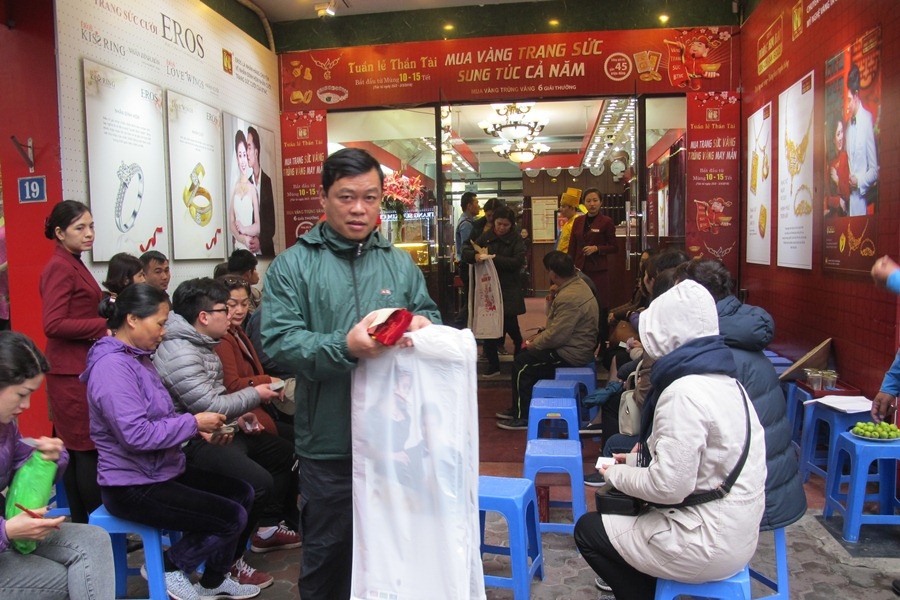Một khách hàng tươi cười khi mua được vàng trong ngày Thần Tài. (Ảnh: Đức Duy/Vietnam+)