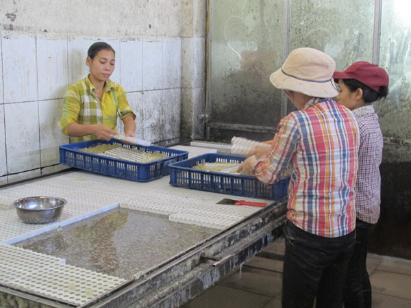 Nhân viên với tay trần, chân đi đất ​đang thoăn thoắt bóc nhân kẹo dẻo (Ảnh: Đức Duy/Vietnam+)