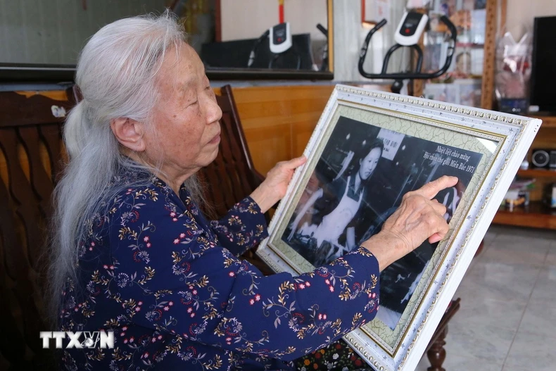 Bà Vũ Thị Bích Liên cùng tấm ảnh chụp khi bà giành được giải Nhất cuộc thi “Hội chọn thợ giỏi miền Bắc,” năm 1971. (Ảnh: Công Luật/TTXVN)