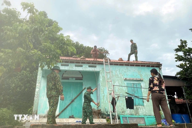 Chiến sỹ Bộ đội Biên phòng đồn Ngọc Vừng (Bộ đội Biên phòng Quảng Ninh) giúp người dân chằng chống nhà cửa trước bão. (Ảnh: Thanh Vân/TTXVN)