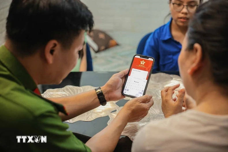 Tổ chuyển đổi số cộng đồng hướng dẫn người dân sử dụng ứng dụng định danh công dân trên môi trường kỹ thuật số (VNeID) có giá trị sử dụng thay thế các giấy tờ truyền thống. (Ảnh: Hoàng Hiếu/TTXVN)