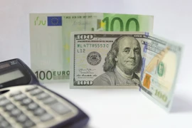 Đồng tiền giấy mệnh giá 100 USD và 100 euro (phía sau) tại Brussels, Bỉ. (Nguồn: THX/TTXVN)