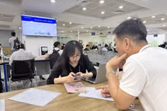 Cán bộ Trung tâm phục vụ hành chính công hướng dẫn người dân lấy số thứ tự online đối với hồ sơ liên quan đến đất đai qua ứng dụng iHanoi. (Ảnh: Quốc Lũy/TTXVN)