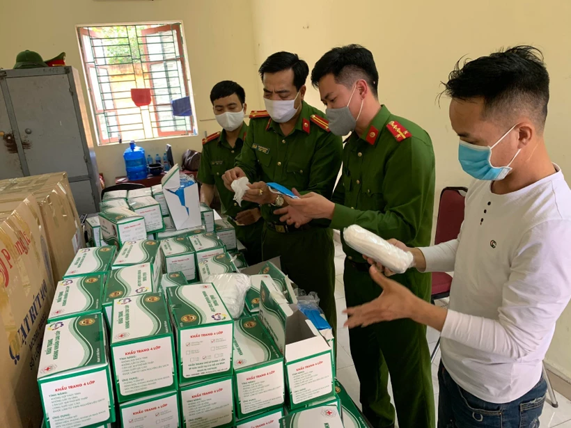 Lực lượng công an kiểm tra lô hàng khẩu trang vừa bị thu giữ. (Nguồn: TTXVN phát)