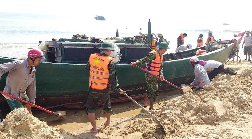 Cán bộ, chiến sĩ bộ đội biên phòng cùng nhân dân địa phương hỗ trợ giải cứu tàu cá gặp nạn. (Ảnh: Võ Dung/TTXVN)