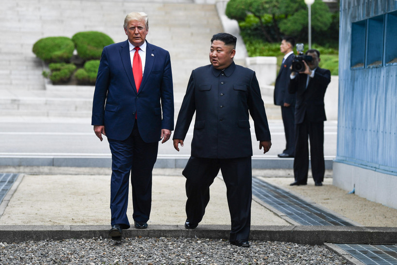 Tổng thống Mỹ Donald Trump (trái) và nhà lãnh đạo Triều Tiên Kim Jong-un bước chân qua đường ranh giới phân chia hai miền Triều Tiên tại DMZ, sang phần lãnh thổ của Triều Tiên chiều 30/6/2019. (Nguồn: AFP/TTXVN)