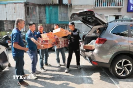 Anh Lỗ Minh Tuấn, Đội trưởng “Đội xe 0 đồng Hà Nội” cùng Tình nguyện viên tiếp nhận hàng hỗ trợ do các tổ chức, cá nhân quyên góp. (Ảnh: Lê Đông/TTXVN)
