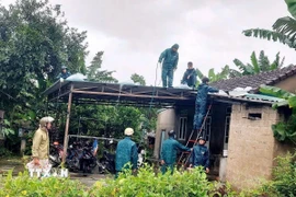 Lực lượng chức năng hỗ trợ, giúp các hộ dân gia cố, chằng chống nhà cửa tránh bão. (Ảnh: TTXVN phát)