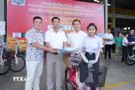 Chủ tịch huyện Naxaithong và Chủ tịch Câu lạc bộ Doanh nghiệp tỉnh Nghệ An tại huyện Naixaithong, thủ đô Viêng Chăn, trao quà cho học sinh nghèo vượt khó. (Ảnh: Xuân Tú/TTXVN)