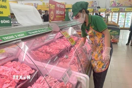 Nhân viên siêu thị thêm hàng vào quầy thực phẩm. (Ảnh: Hương Giang/TTXVN)