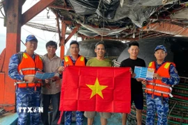 Cán bộ chiến sỹ Vùng Cảnh sát biển 2 kết hợp tuyên truyền với tặng hàng nghìn cờ Tổ quốc cho ngư dân làm ăn trên biển. (Ảnh: Đoàn Hữu Trung/TTXVN)