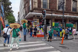 Người bán hàng chào bán mẫu áo đấu đội tuyển Mexico để thu hút khách mua. (Ảnh: Phương Lan/TTXVN)